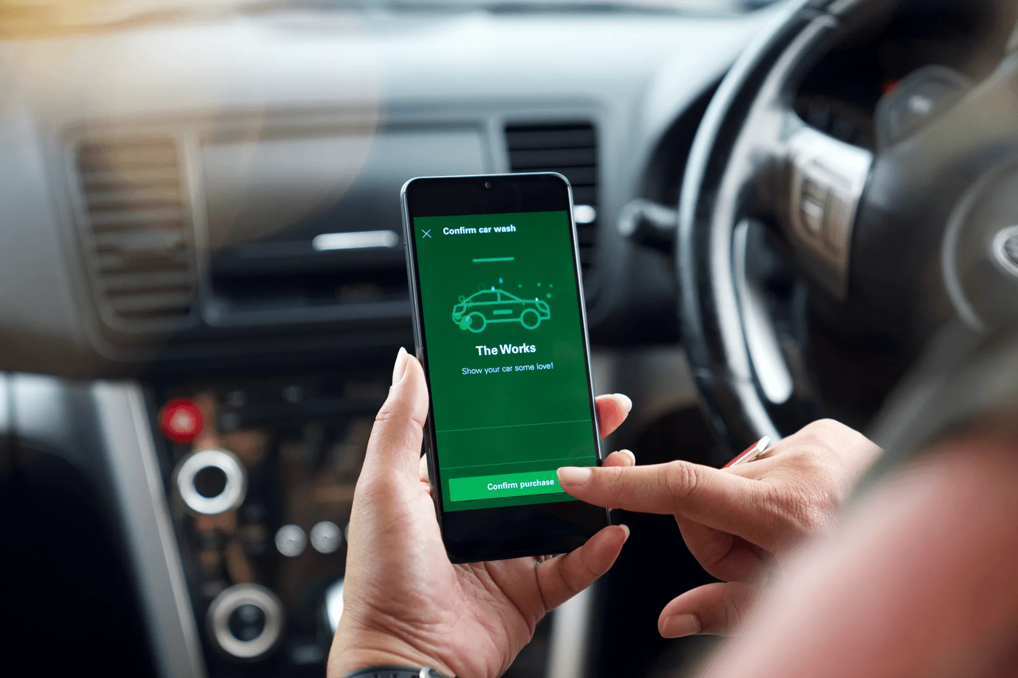 Driver sitting in their car confirming a car wash purchase on the BPme app