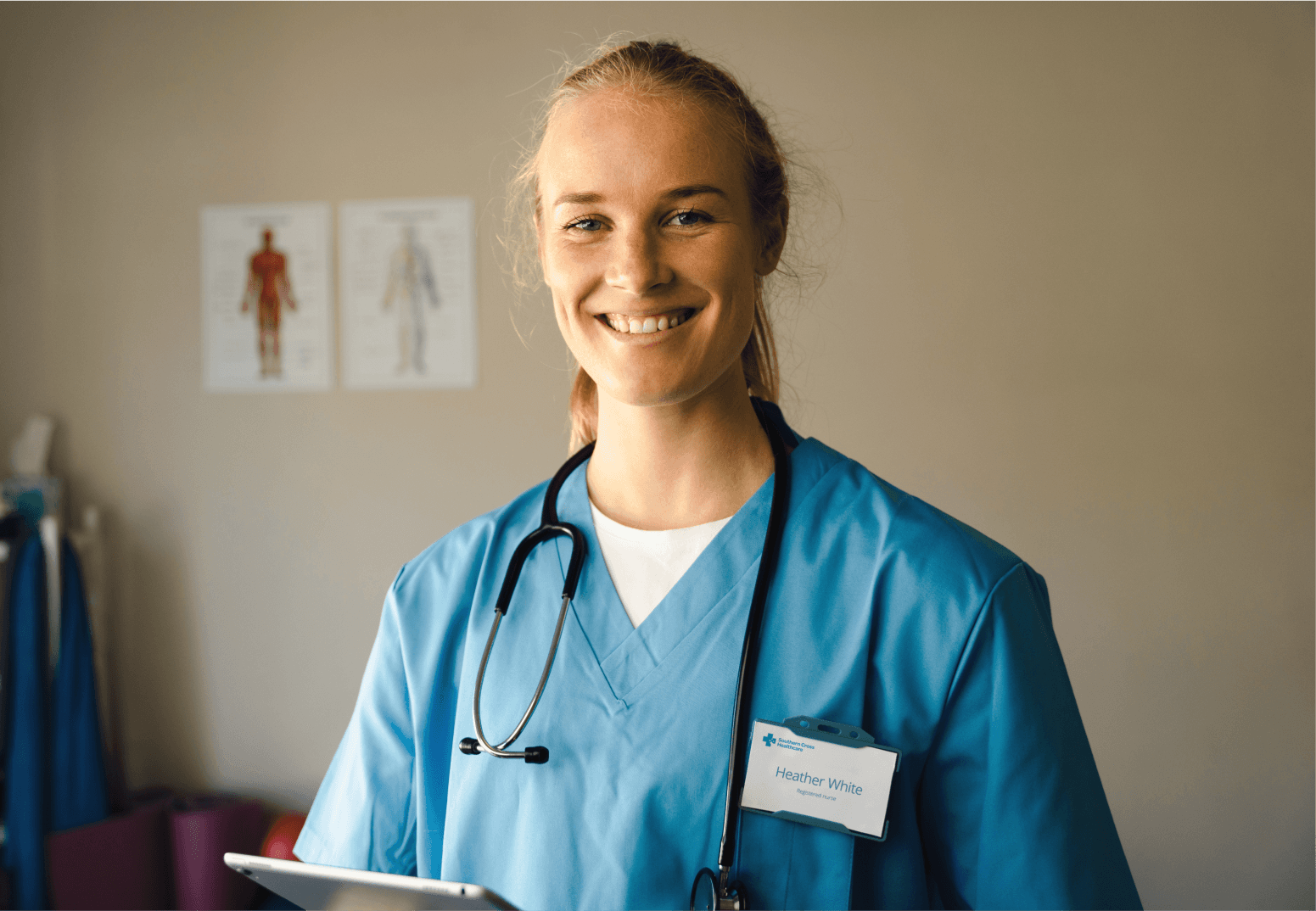 Smiling Southern Cross Healthcare nurse in blue scrubs holding a tablet, with a stethoscope around her neck