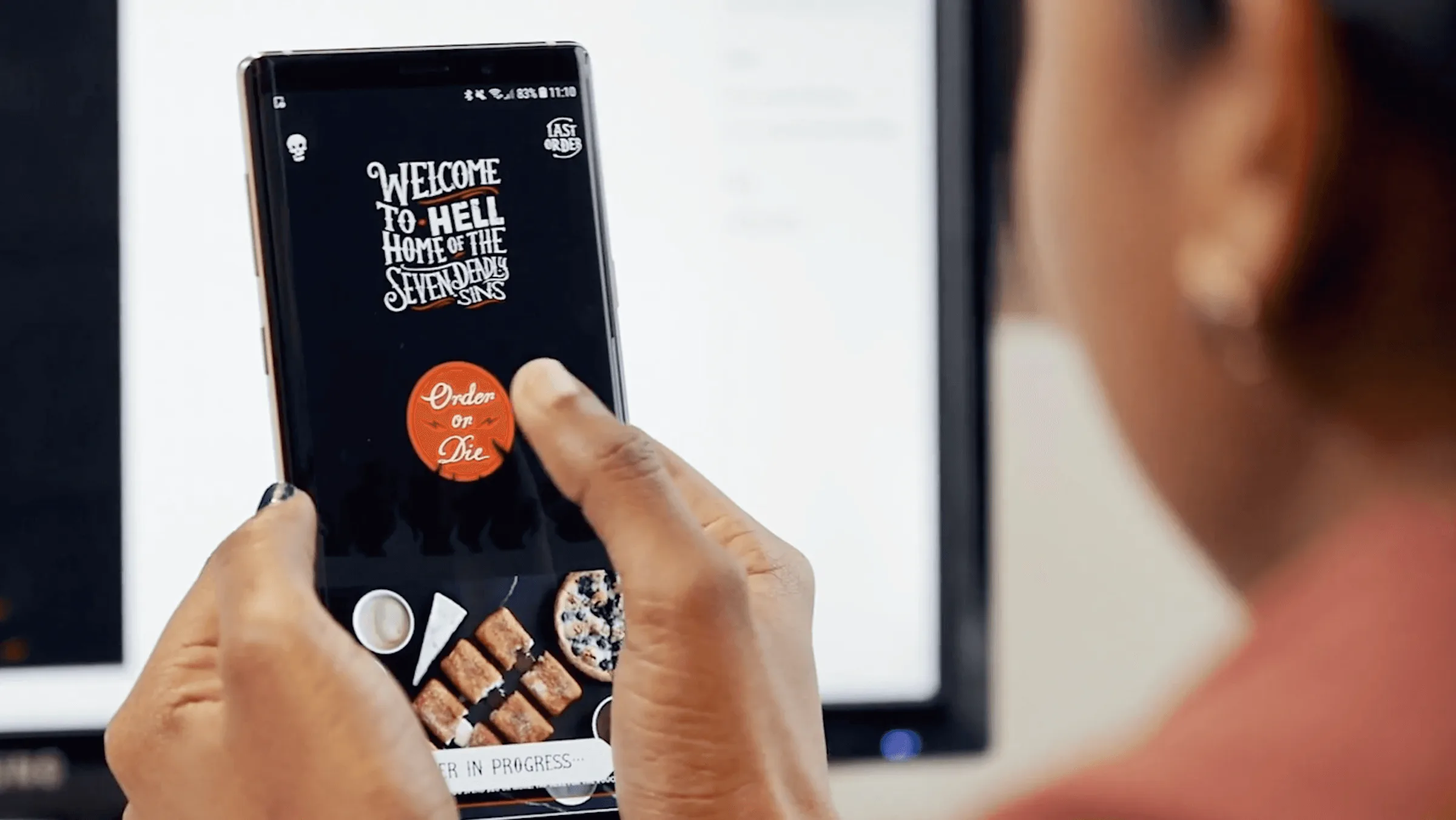 Customer holding a phone showing the Hell Pizza app welcome screen and tapping its 'Order or Die' button