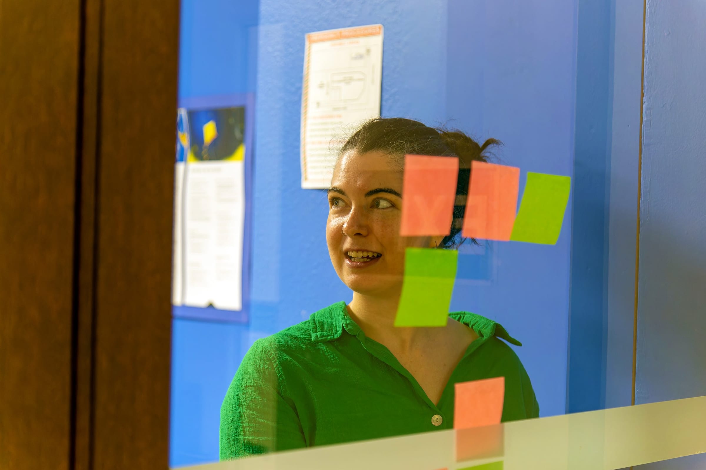 A PaperKiter seen through a glass wall, carefully placing post-it notes, symbolizing a focused approach to getting to the heart of the matter