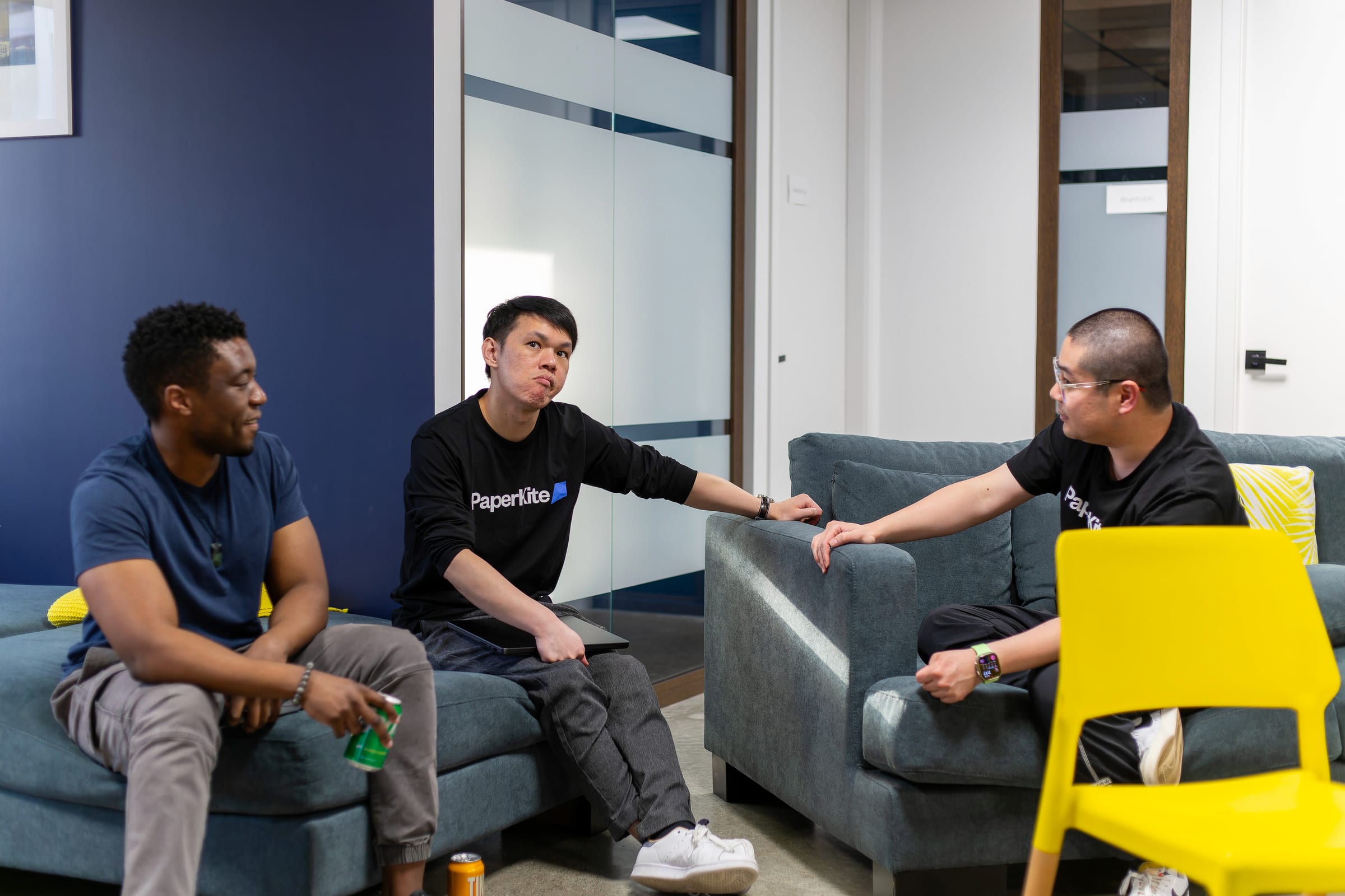 A group of PaperKiters sitting on couches, engaged in a thoughtful conversation with one team member deep in thought